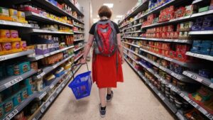 A shopper walking through the aisle of a supermarket in London.